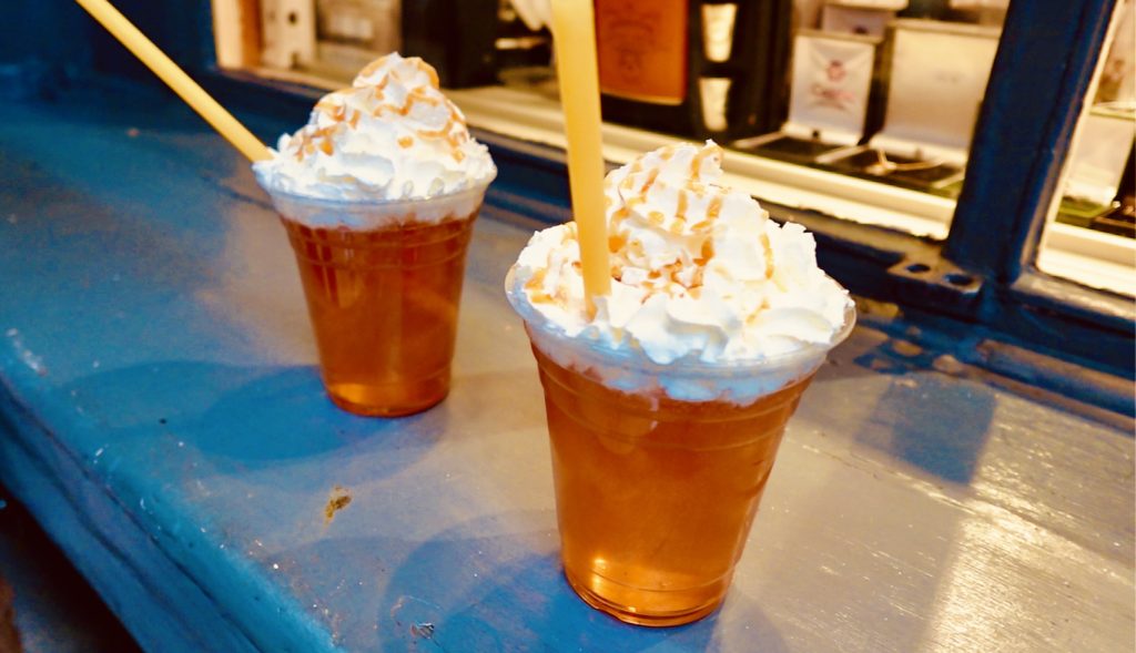 Two cups of beer with whipping cream and caramel sauce on top.