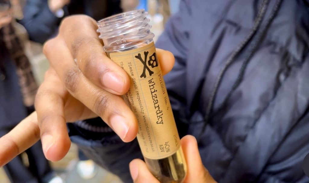 Person holding a bottle decorated with poison label